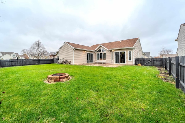 back of property with a lawn and an outdoor fire pit