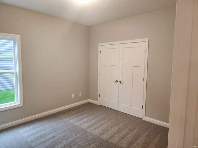 unfurnished bedroom with carpet flooring, a closet, and a textured ceiling