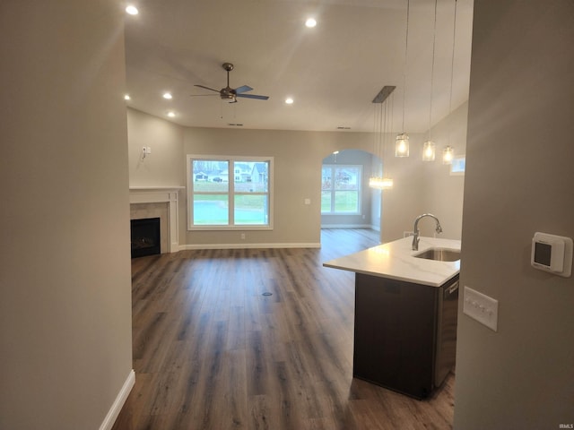 kitchen with a center island with sink, sink, hanging light fixtures, dark hardwood / wood-style floors, and ceiling fan