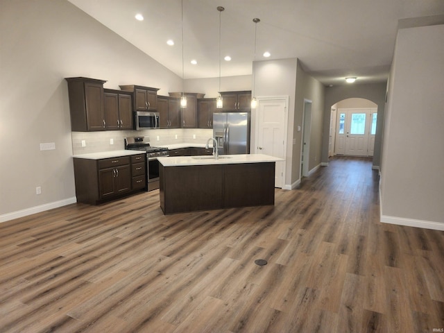 kitchen featuring a center island with sink, hanging light fixtures, dark hardwood / wood-style floors, dark brown cabinetry, and stainless steel appliances