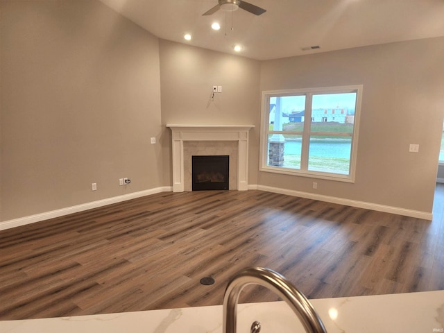 unfurnished living room featuring ceiling fan, dark hardwood / wood-style flooring, and a tiled fireplace