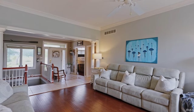 living room featuring ceiling fan, wood-type flooring, crown molding, and decorative columns