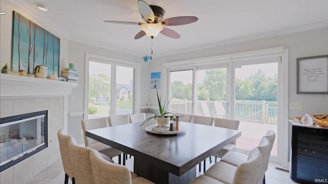 dining room with a wealth of natural light, a fireplace, light tile patterned flooring, and ornamental molding