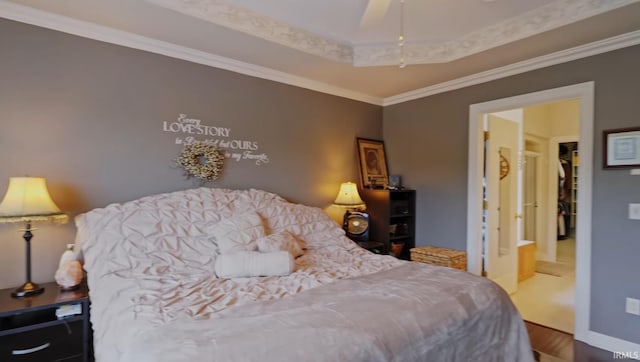 bedroom featuring a raised ceiling, ceiling fan, crown molding, hardwood / wood-style floors, and connected bathroom