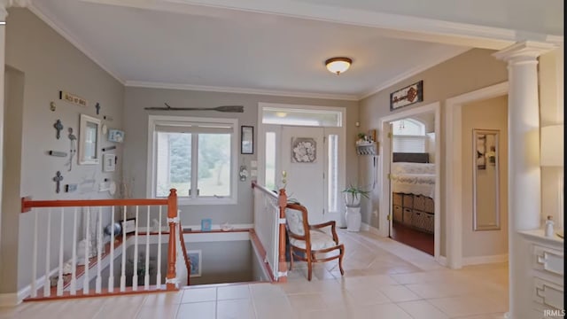 foyer entrance with light tile patterned floors, crown molding, and decorative columns