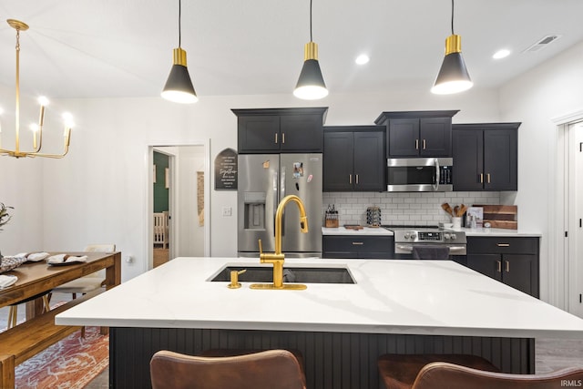 kitchen featuring a kitchen island with sink, decorative light fixtures, and appliances with stainless steel finishes