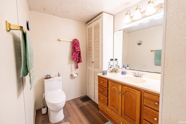 bathroom with vanity, toilet, wood-type flooring, and a textured ceiling