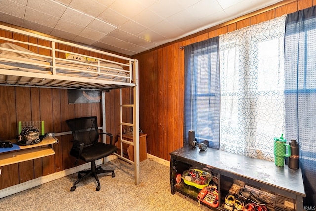 carpeted bedroom featuring wood walls