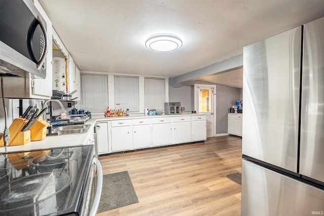 kitchen with sink, white cabinetry, stainless steel appliances, and light hardwood / wood-style flooring