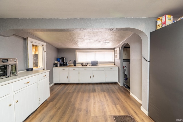 kitchen featuring white cabinets, a textured ceiling, and hardwood / wood-style flooring