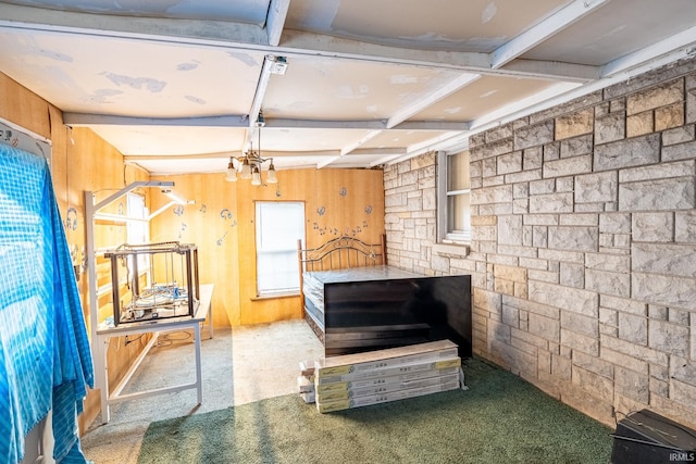 interior space featuring beamed ceiling, carpet, wooden walls, and a notable chandelier