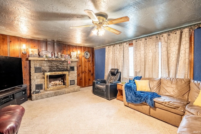 living room with ceiling fan, light colored carpet, a fireplace, and wooden walls