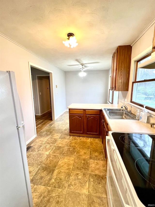 kitchen with kitchen peninsula, a textured ceiling, white appliances, ceiling fan, and sink