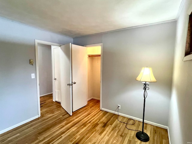 unfurnished bedroom with a closet, ornamental molding, and hardwood / wood-style flooring