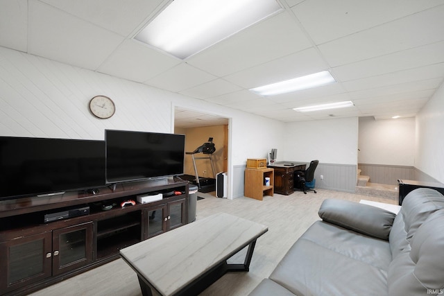 living room featuring a paneled ceiling and wooden walls