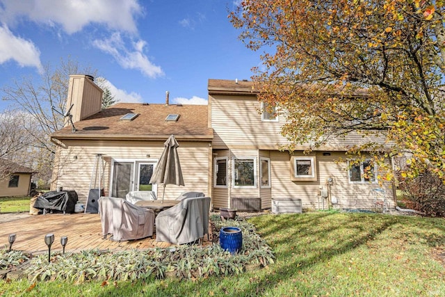 rear view of property featuring a lawn and a deck