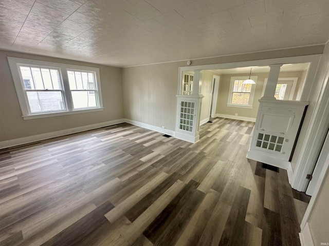 unfurnished living room with decorative columns and hardwood / wood-style flooring