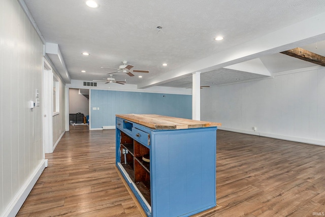 kitchen featuring wooden counters, a kitchen island, blue cabinets, and dark wood-type flooring