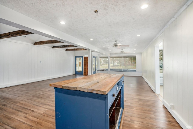 kitchen featuring beam ceiling, a center island, wooden counters, blue cabinets, and wood-type flooring