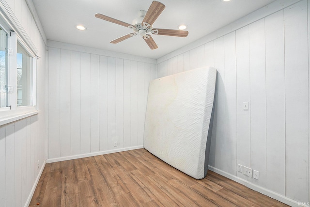 unfurnished room featuring wooden walls, ceiling fan, and light hardwood / wood-style floors