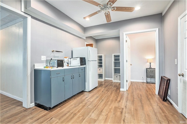 kitchen featuring ceiling fan, light hardwood / wood-style floors, and wooden walls