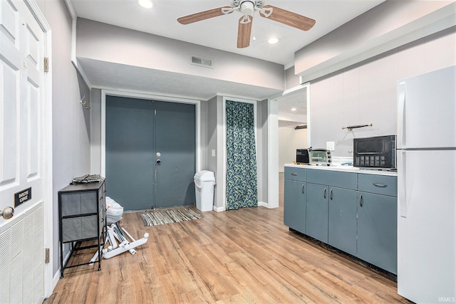 kitchen with ceiling fan, light hardwood / wood-style flooring, blue cabinets, and white refrigerator