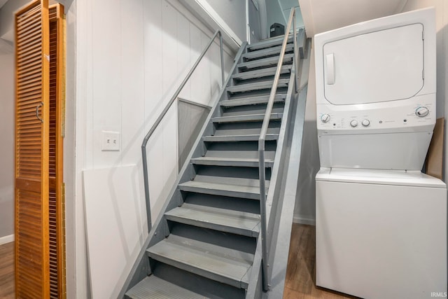 stairway with hardwood / wood-style floors and stacked washer / drying machine