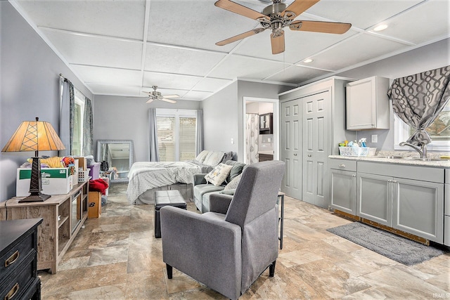 bedroom with ceiling fan, multiple windows, and sink