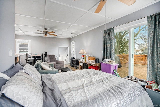 bedroom with access to exterior, a paneled ceiling, hardwood / wood-style flooring, and ceiling fan