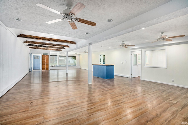 spare room featuring ceiling fan, beamed ceiling, a textured ceiling, and light wood-type flooring