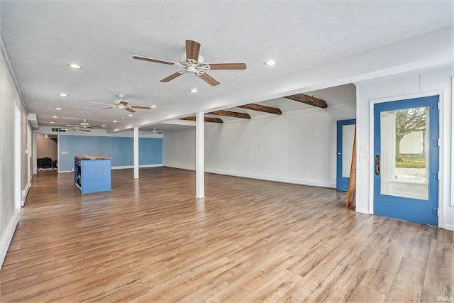 interior space featuring beamed ceiling, light hardwood / wood-style floors, and a textured ceiling