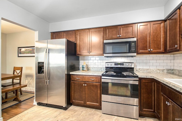 kitchen with backsplash, light hardwood / wood-style flooring, and appliances with stainless steel finishes