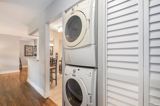 washroom featuring stacked washing maching and dryer and dark wood-type flooring