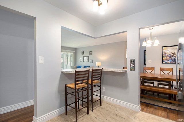 interior space featuring hardwood / wood-style flooring, a notable chandelier, a kitchen bar, and hanging light fixtures