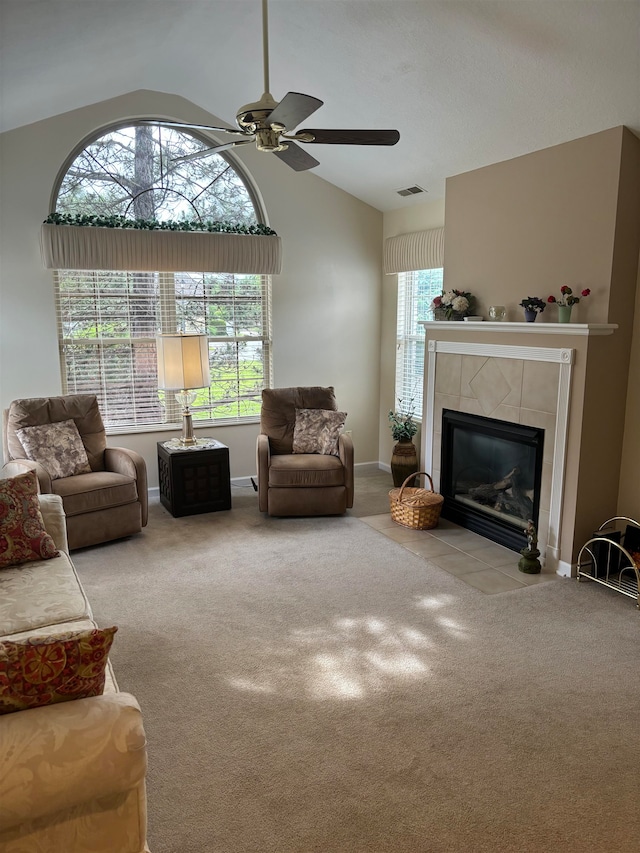 carpeted living room with ceiling fan, a fireplace, and high vaulted ceiling