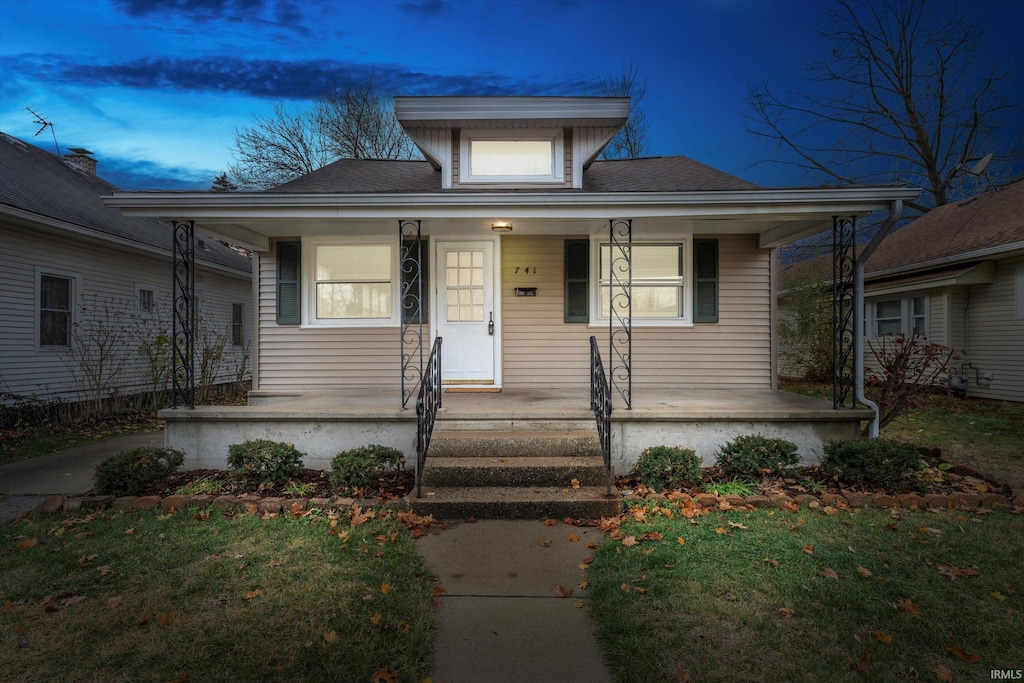 bungalow-style house featuring a porch and a yard