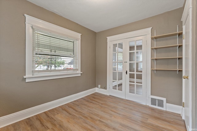 spare room with french doors and light hardwood / wood-style flooring