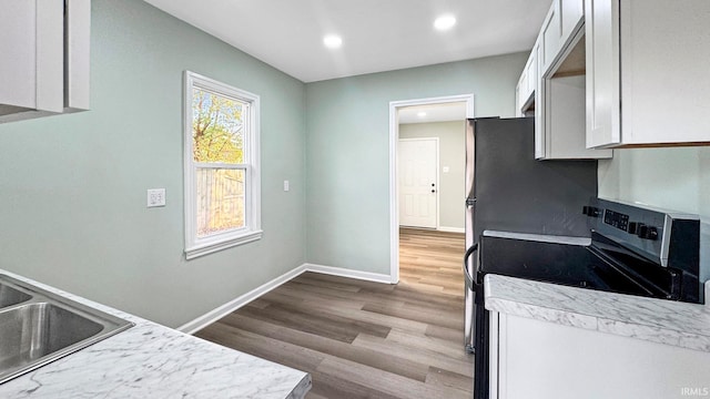 kitchen featuring white cabinetry, light hardwood / wood-style flooring, stainless steel electric range oven, and sink