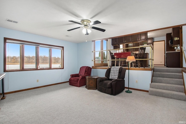 living area with light carpet and ceiling fan