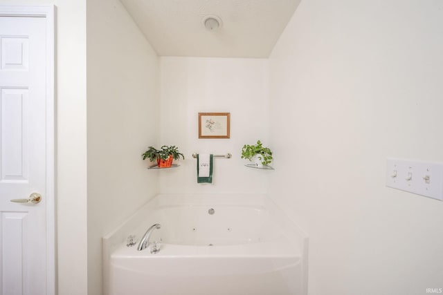 bathroom featuring a textured ceiling and a tub to relax in