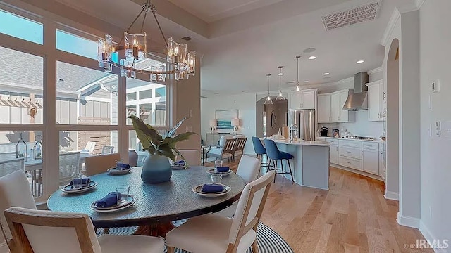 dining room featuring crown molding, light hardwood / wood-style floors, and a notable chandelier