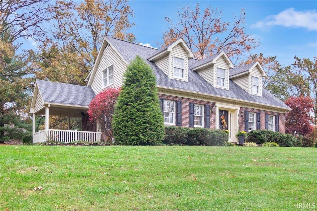 new england style home with a porch and a front lawn