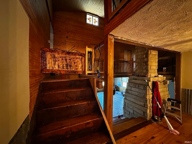 stairs featuring hardwood / wood-style flooring, wood walls, and vaulted ceiling