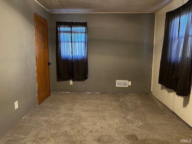 carpeted empty room featuring a textured ceiling