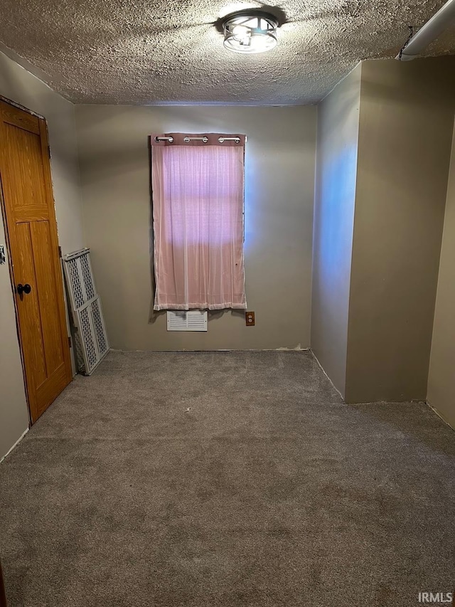 carpeted empty room featuring a textured ceiling