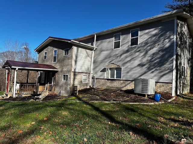 back of property featuring central AC unit, covered porch, and a lawn