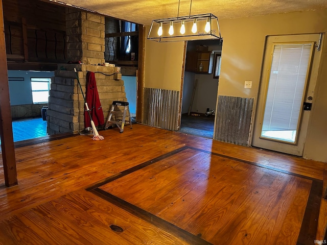 unfurnished dining area with wood-type flooring and a textured ceiling