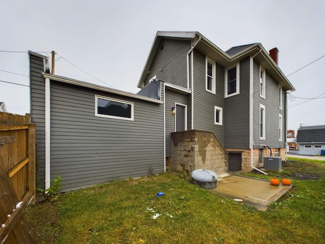 back of property with a yard and central AC