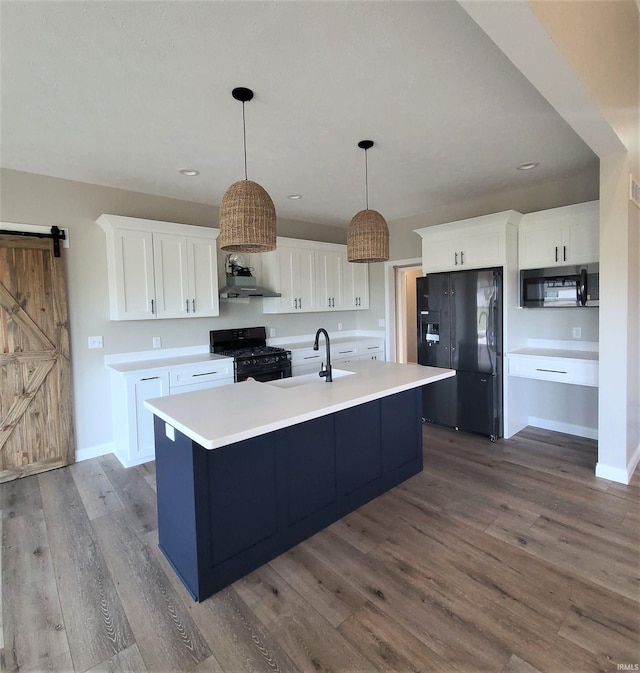 kitchen featuring white cabinetry, sink, hanging light fixtures, a barn door, and black appliances