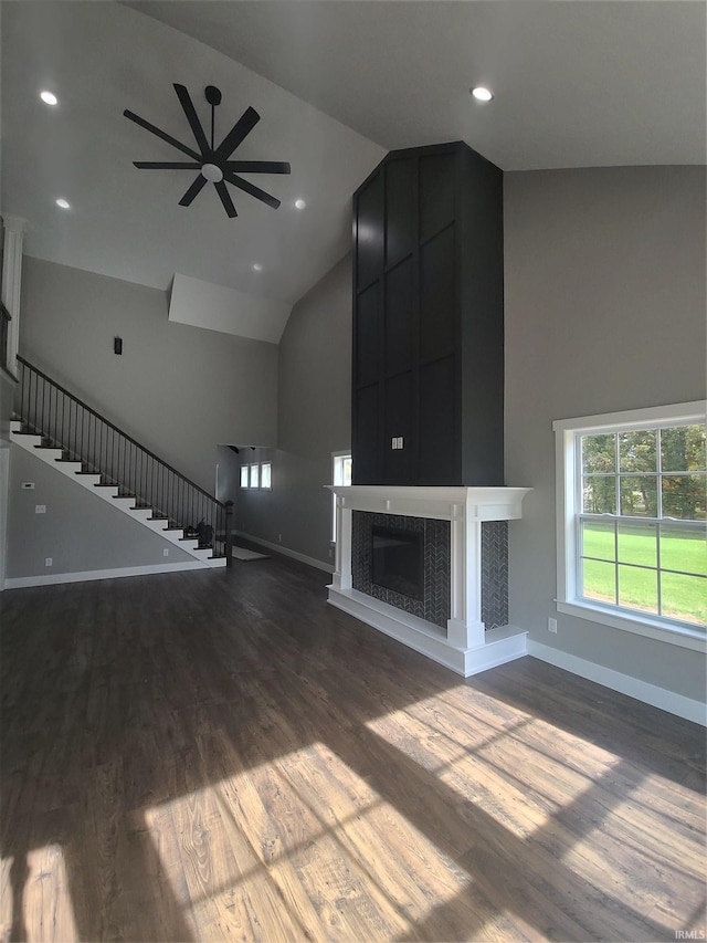 unfurnished living room featuring a tiled fireplace, ceiling fan, hardwood / wood-style floors, and high vaulted ceiling